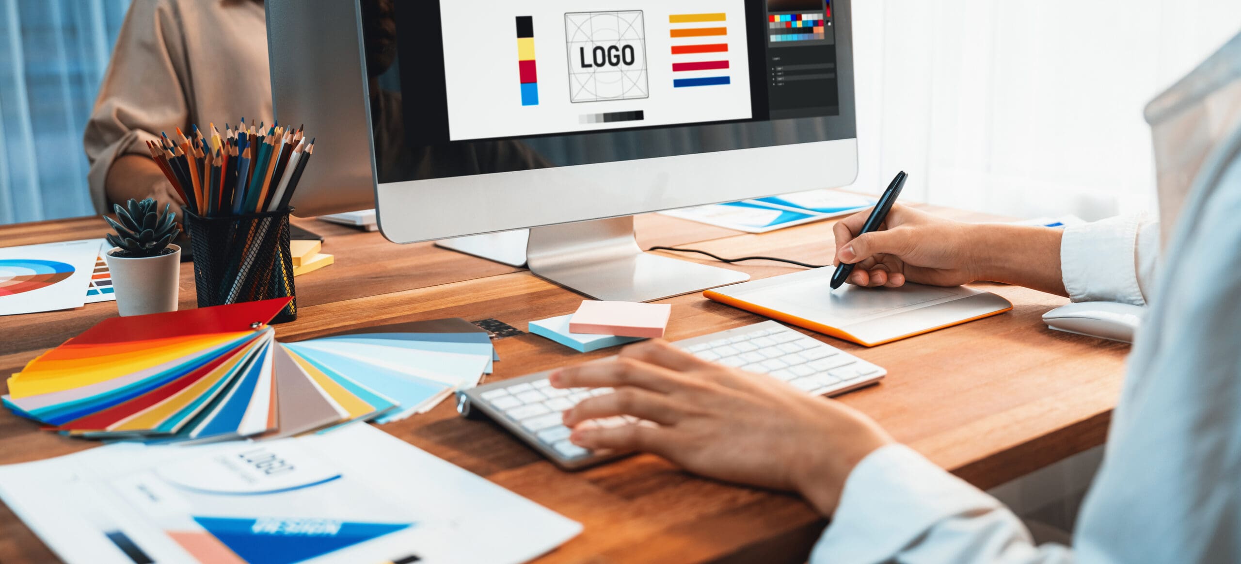 Graphic designer work on computer laptop and with graphic drawing pen while brainstorming unique design with professional graphic team in modern digital studio workplace. Panorama shot. Scrutinize